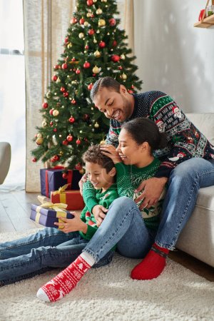 vertikale Aufnahme einer fröhlichen afrikanisch-amerikanischen Familie, die Zeit miteinander verbringt und sich herzlich umarmt, Weihnachten