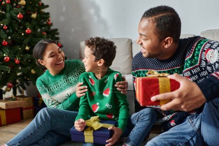 joyeuse famille afro-américaine passer du bon temps ensemble tenant des cadeaux le matin de Noël