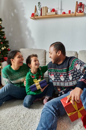 tiro vertical de la familia afroamericana feliz en suéteres acogedores pasar tiempo juntos, Navidad