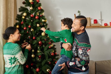 happy african american family spending time together smiling cheerfully decorating Christmas tree