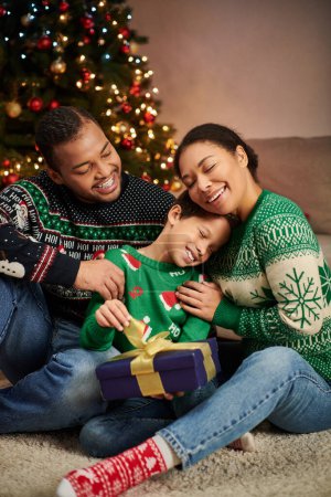 vertikale Aufnahme einer liebevollen afrikanisch-amerikanischen Familie, die sich herzlich umarmt und glücklich lächelt, Weihnachten