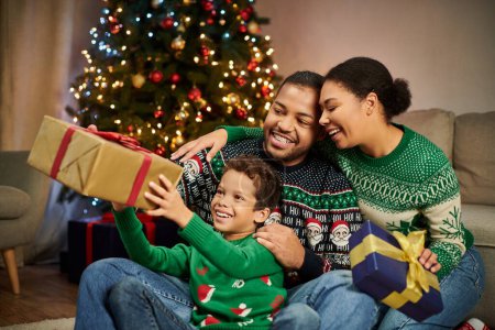 freudig liebende afrikanisch-amerikanische Familie tauscht an Heiligabend Geschenke aus und umarmt sich herzlich