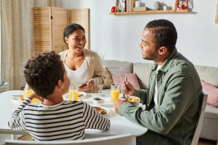 glückliche afrikanisch-amerikanische Familie in lässiger Kleidung, die sich beim Frühstück liebevoll anlächelt