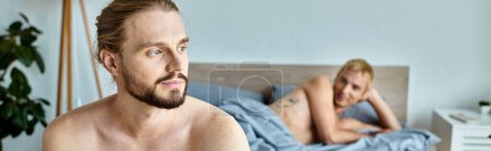 homme barbu rêveur et positif regardant loin près partenaire gay couché sur le lit, bonheur, bannière
