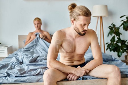 Téléchargez les photos : Offensé barbu gay l'homme en caleçon assis près de l'amour partenaire dans chambre à coucher, troublé relation - en image libre de droit