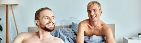 alegre pareja gay sonriendo en acogedor dormitorio por la mañana, serenidad y armoniosa relación, bandera