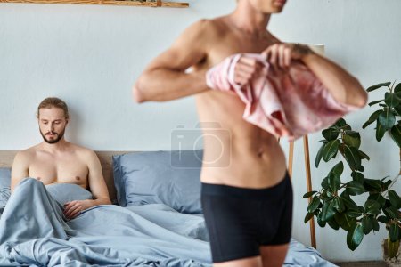bouleversé barbu gay l'homme assis sur lit près de l'amour partenaire habillage jusqu 'dans chambre à coucher, relations problèmes