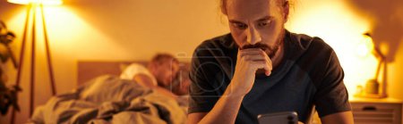 disloyal gay man browsing internet on smartphone near partner sleeping at night in bedroom, banner