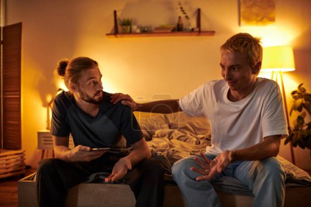 entmutigt Homosexuell Mann streitet mit Freund sitzen mit Smartphone in der Nacht im Schlafzimmer, betrügen