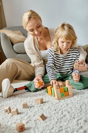 girl with prosthetic leg sitting on carpet and playing with wooden blocks near happy mother