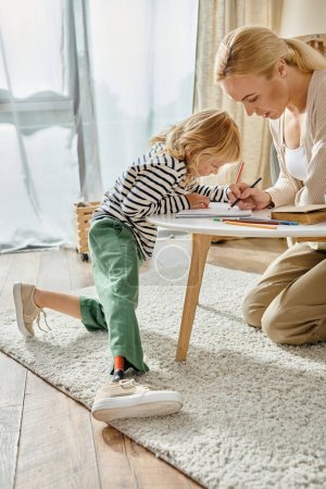 Téléchargez les photos : Mère et enfant avec jambe prothétique dessinant ensemble sur papier avec crayons colorés, temps de qualité - en image libre de droit