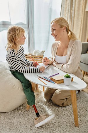 Téléchargez les photos : Mère et enfant avec dessin de jambe prothétique sur papier avec crayons colorés ensemble, temps de qualité - en image libre de droit