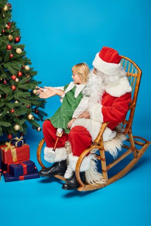 Foto de Chica feliz con la pierna protésica sentado en vueltas de Santa Claus al lado del árbol de Navidad decorado - Imagen libre de derechos