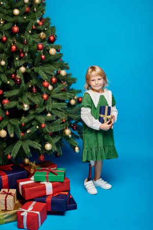 blonde little girl with prosthetic leg standing next to Christmas tree with wrapped presents