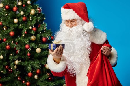 Santa Claus with beard and eyeglasses in red costume holding sack bag and Christmas present