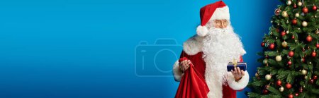 Santa Claus with beard and eyeglasses in red costume holding sack bag and Christmas present, banner