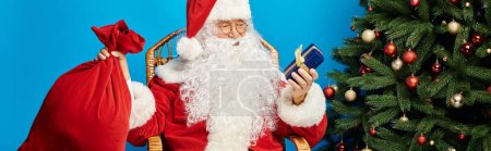 happy Santa Claus sitting in rocking chair with gift box and sack bag near Christmas tree, banner