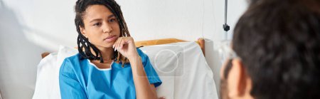 Téléchargez les photos : Attrayant malade afro-américain femme couché dans le lit d'hôpital écoute jeune médecin indien, bannière - en image libre de droit