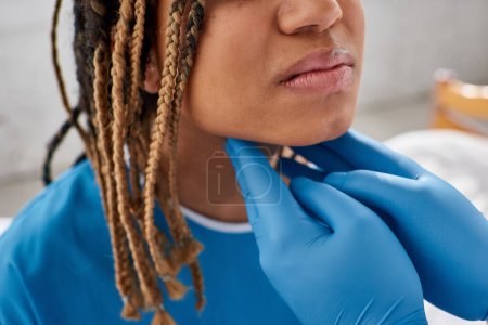 Foto de Vista recortada del médico indio examinando los ganglios linfáticos de su paciente afroamericano enfermo - Imagen libre de derechos