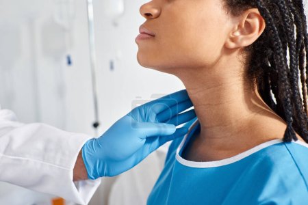 Téléchargez les photos : Vue recadrée de femme afro-américaine malade lorsque son médecin indien examine ses ganglions lymphatiques - en image libre de droit