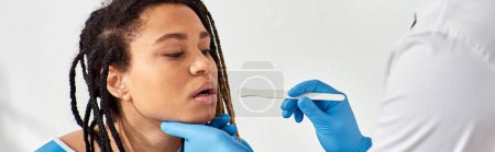 Foto de Joven mujer afroamericana enferma en la sala de hospital que tiene médico chequeo de garganta, atención médica - Imagen libre de derechos