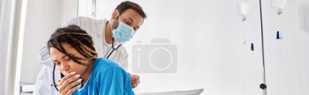 Téléchargez les photos : Jeune médecin indien examinant le souffle de son patient afro-américain malade avec stéthoscope, bannière - en image libre de droit