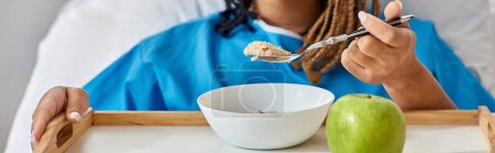 Téléchargez les photos : Vue recadrée de jeune femme afro-américaine malade prenant son petit déjeuner dans un lit d'hôpital, bannière - en image libre de droit
