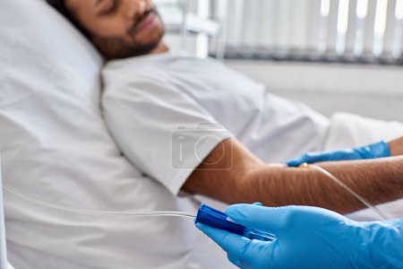 Téléchargez les photos : Focus sur la main de l'infirmière afro-américaine réglage drop counter avec patient indien mâle sur toile de fond - en image libre de droit
