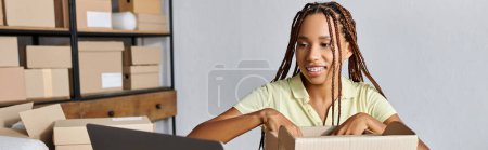 Foto de Alegre atractivo africano americano mujer caja de embalaje vendedor y mirando portátil, entrega, bandera - Imagen libre de derechos