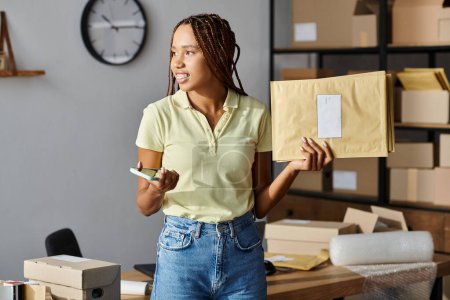 attrayant joyeux vendeur afro-américain femme tenant des paquets de courrier et téléphone et détournant les yeux