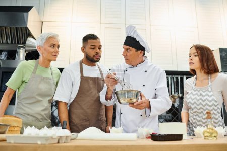 mature chef in white hat showing how to whisk dough to his diverse students, confectionary