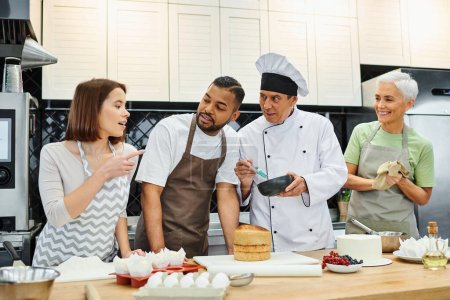 fröhliche multiethnische Menschen in Schürzen diskutieren während des Unterrichts, wie man mit einem reifen Koch kocht