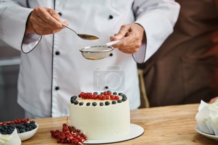 Téléchargez les photos : Vue recadrée du chef masculin mature décorant son délicieux gâteau professionnellement, cours de cuisine - en image libre de droit
