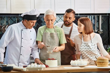 mujer madura en delantal decorando pastel delante del chef y sus diversos amigos, cursos de cocina