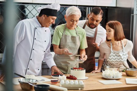 mature woman decorating cake next to her cheerful interracial friends and chef, cooking courses