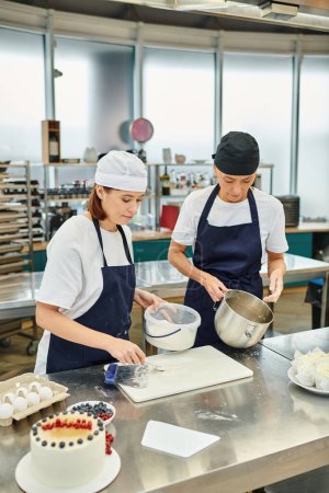 good looking female chefs in blue aprons and toques working with dough together, confectionery