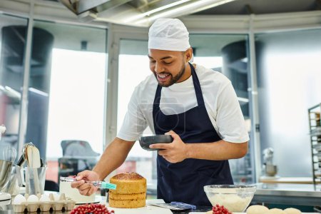 Téléchargez les photos : Joliment beau chef afro-américain en toque bleue et tablier en utilisant une brosse en silicone sur un délicieux gâteau - en image libre de droit
