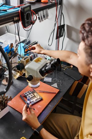 Téléchargez les photos : Homme flou assemblage micro schémas de dispositif électronique près de l'équipement professionnel dans l'atelier - en image libre de droit