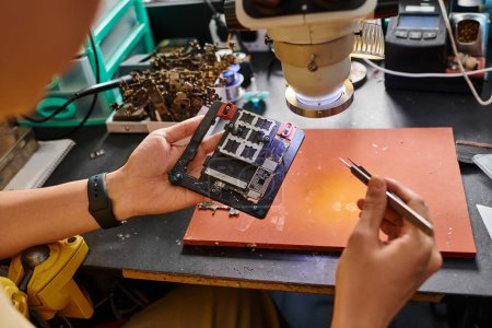 Ausgeschnittene Ansicht eines professionellen Technikers, der in der Reparaturwerkstatt einen Satz elektronischer Geräte untersucht