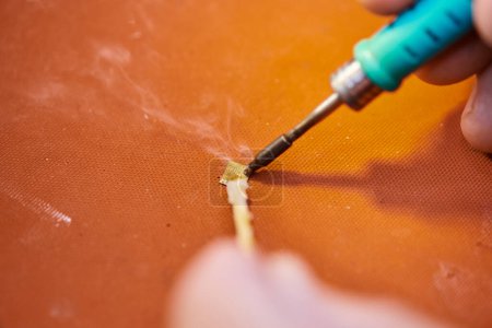 Photo for Partial view of skilled technician soldering chipset of modern electronic device in private workshop - Royalty Free Image