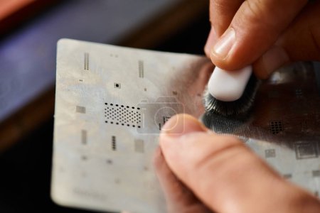 Nahaufnahme des gelernten Technikers, der in der Werkstatt Mikroschema mit Pinsel reinigt