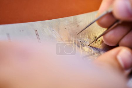 Photo for Cropped view of professional technician with tweezers near electronic microscheme in workshop - Royalty Free Image