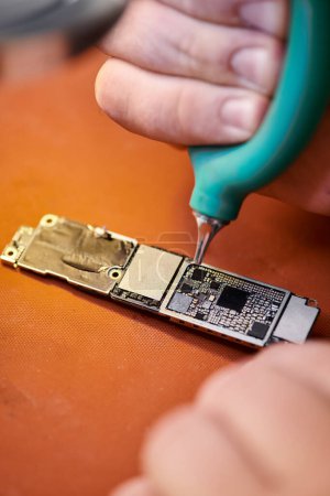 Teilansicht des Reparateurs, der elektronisches Mikroschema reinigt, während er in einer privaten Werkstatt arbeitet