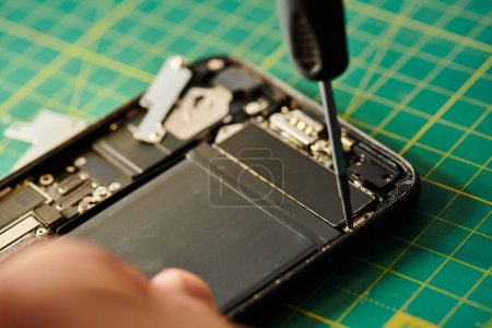 zugeschnittene Ansicht des Reparateurs, der sein Handy testet, während er in einer privaten Werkstatt arbeitet, Kleinunternehmen