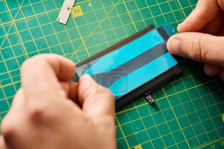 Téléchargez les photos : Vue recadrée du réparateur professionnel testant la batterie de téléphone portable dans l'atelier, petite entreprise - en image libre de droit