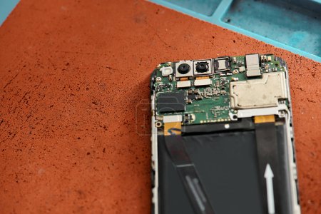 vue de dessus du téléphone cellulaire cassé démonté sur la table dans l'atelier moderne, entreprise de réparation d'équipement