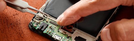 cropped view of skilled technician disconnecting battery of smartphone with tweezers, banner