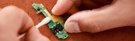 close up view of repairman cleaning electronic microscheme with cotton swab, horizontal banner