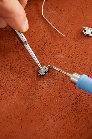 cropped view of professional technical specialist soldering electronic circuit in private workshop