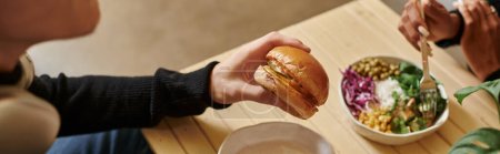 banner of man enjoying vegan meal while holding burger with tofu near blurred woman eating salad
